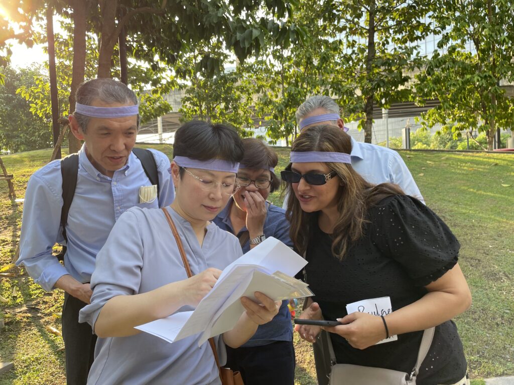 A diverse team is participating in a team-building activity, examining a paper together in an outdoor setting, embodying the best team building in Bangkok.